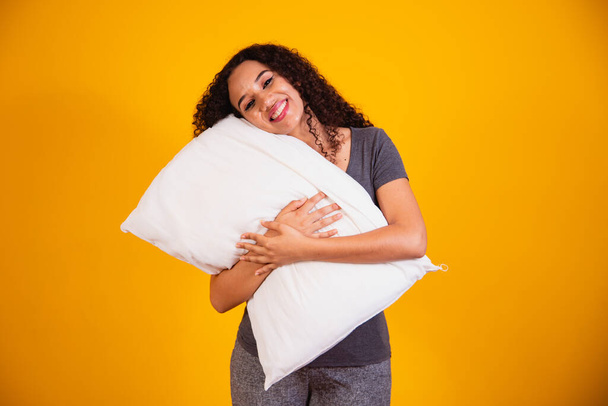 Φωτογραφία ενός ονειρεμένου κοριτσιού που αγκαλιάζει το νυσταλέο μαξιλάρι σε κίτρινο φόντο με ελεύθερο χώρο για κείμενο. - Φωτογραφία, εικόνα