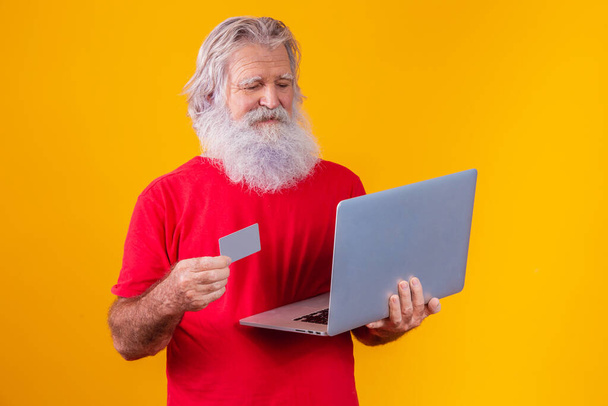 Elderly man holding laptop computer and bank credit card. Online shopping transaction. Mobile banking cashless method. - Fotoğraf, Görsel