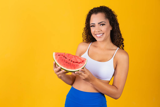 Beautiful young afro woman posing with watermelon on yellow background - Photo, image
