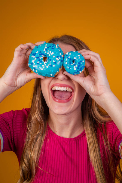 Portrait of a cheery pretty girl holding blue donuts at her face - Foto, immagini