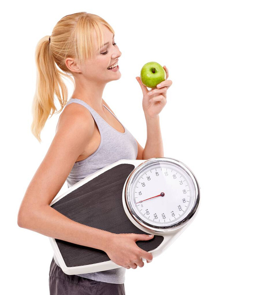 Weight-loss through healthy eating. A woman holding a scale and eating an apple - Foto, Imagem