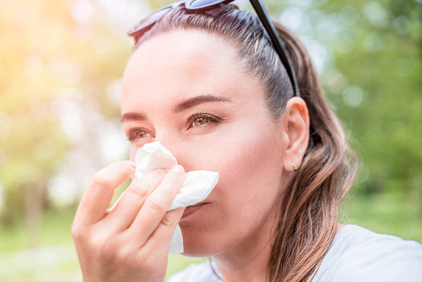 Młoda kobieta cierpiąca na alergię na świeżym powietrzu. Objawy alergii na pyłki. - Zdjęcie, obraz
