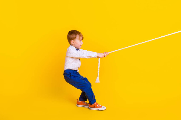 Profile side full body photo of little boy feel strong complete challenge tug war isolated on bright color background. - Фото, изображение