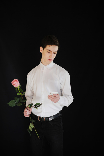 młody człowiek z róży patrząc na telefon - Zdjęcie, obraz