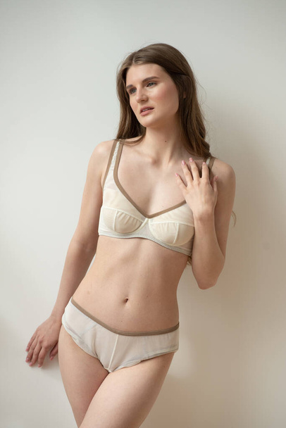 beautiful young woman in a white lingerie on a light background - Valokuva, kuva