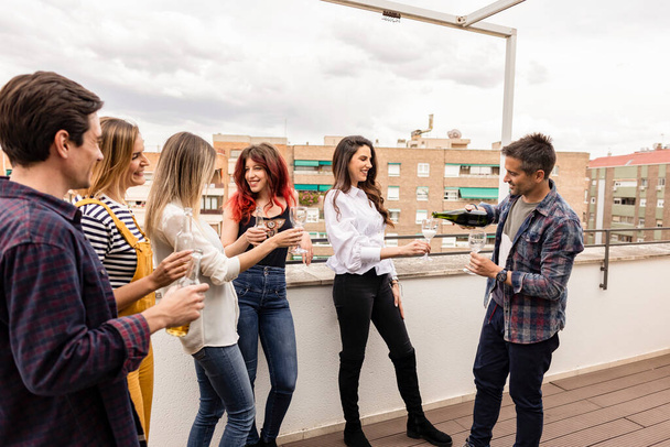 group of smiling friends, happy, delighted, in good mood, celebrate birthday, drink champagne outside on rooftop - Photo, Image