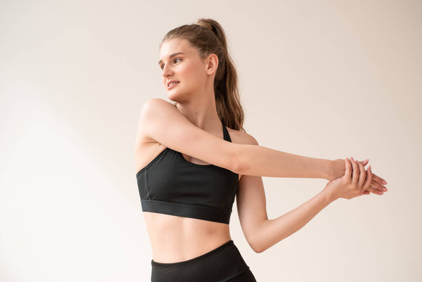 jong mooi vrouw in sportkleding doen stretching oefeningen op witte achtergrond - Foto, afbeelding