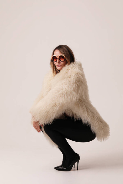 Vertical portrait of young woman wearing white fur coat posing indoor. Mock-up. High quality photo. - Foto, imagen