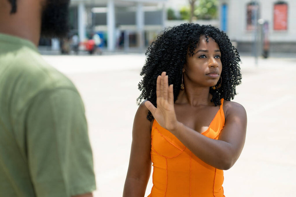 Brazilian woman gesturing stop to boyfriend in discussion outdoor in summer in city - 写真・画像