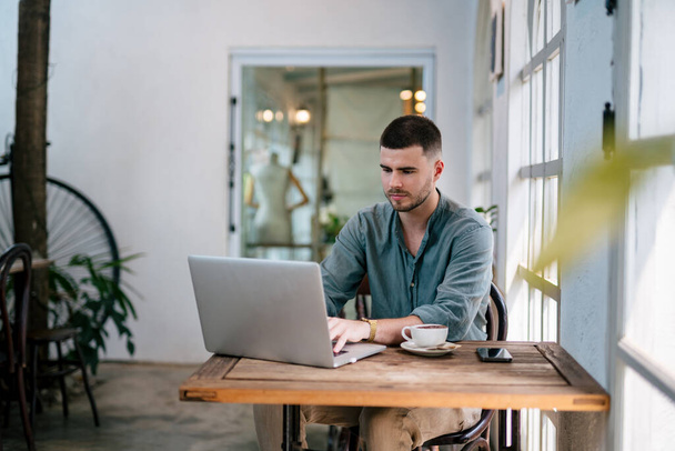 Um homem de barba Freelancer bonito usando um laptop sentado em uma mesa. conceito freelance. - Foto, Imagem