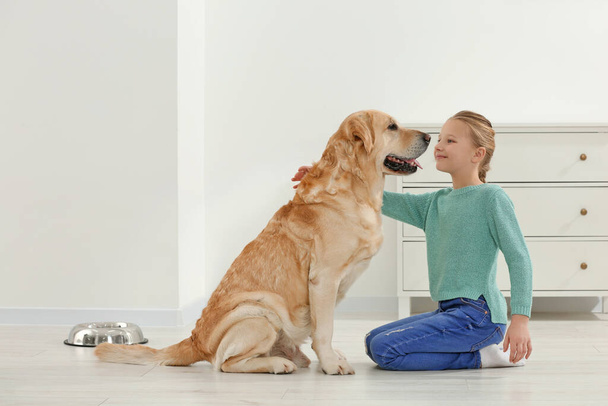 Cute child with her Labrador Retriever on floor at home. Adorable pet - Valokuva, kuva