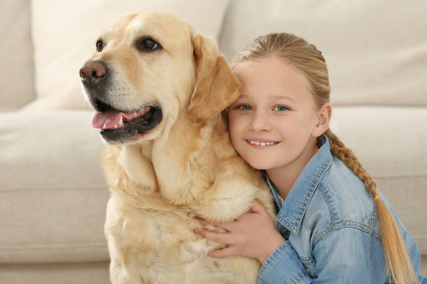 Cute child with her Labrador Retriever indoors. Adorable pet - Foto, afbeelding