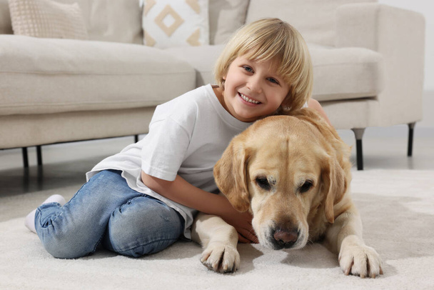 Cute little child with Golden Retriever on floor at home. Adorable pet - Foto, immagini
