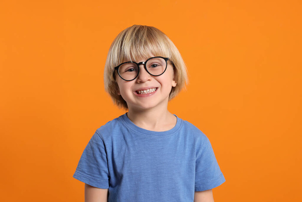 Cute little boy wearing glasses on orange background - 写真・画像