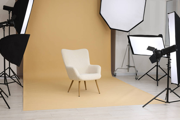 Interior of modern photo studio with armchair and professional lighting equipment - Foto, immagini