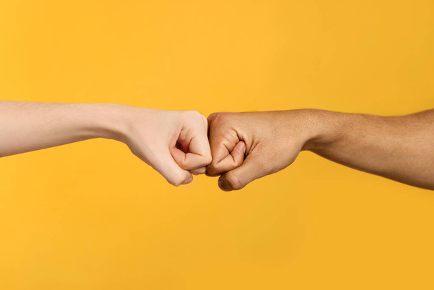 International relationships. People making fist bump on orange background, closeup - Foto, Imagen