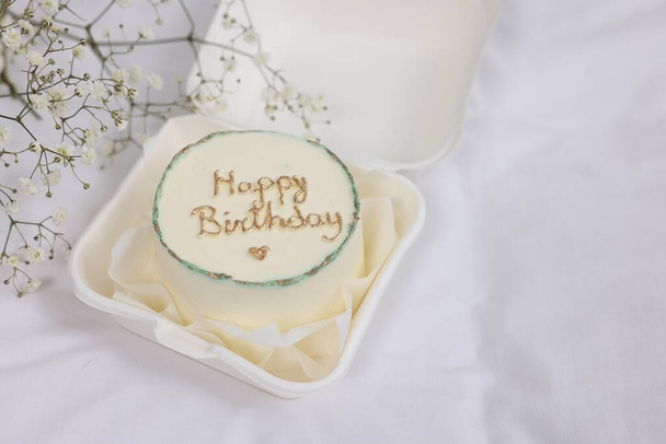 Delicious decorated Birthday cake near dry flowers on white cloth, space for text - Fotografie, Obrázek