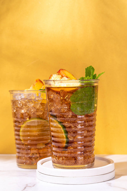 Jääpersikka teetä, tai persikka limonadi limetti, minttu, murskattu jää ja baari astiat korkea-värinen kultainen beige tausta  - Valokuva, kuva