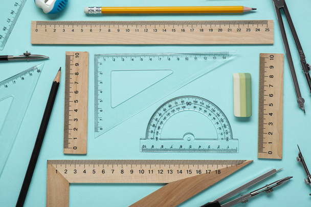 Flat lay composition with different rulers and protractor on turquoise background - Foto, imagen