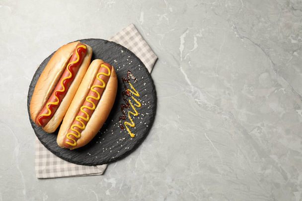 Delicious hot dogs with mustard and ketchup on light grey table, top view. Space for text - Fotografie, Obrázek