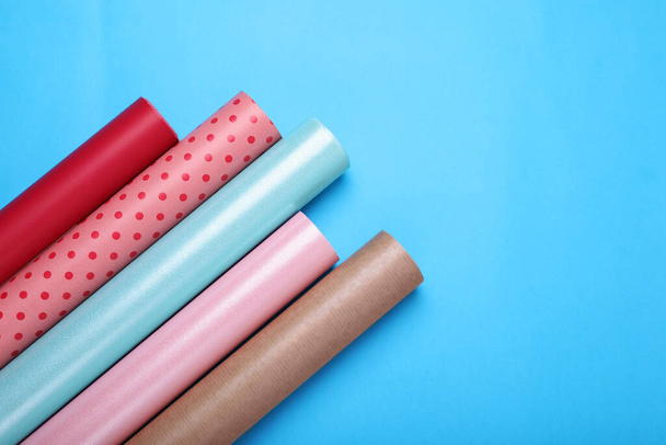 Rolls of wrapping papers on light blue background, flat lay. Space for text - Foto, afbeelding