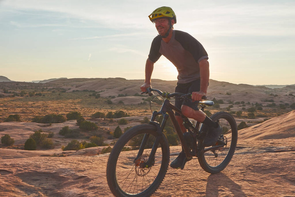 Il ciclismo quotidiano ha enormi vantaggi. Scatto completo di un giovane atleta di sesso maschile in mountain bike nel deserto - Foto, immagini