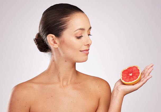 The holy grail of healthy skin. an attractive young woman holding a grapefruit against a studio background - Foto, immagini