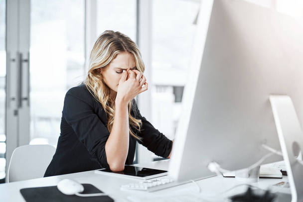 Le stress au travail fait une autre victime. une jeune femme d'affaires éprouvant du stress tout en travaillant à son bureau dans un bureau moderne - Photo, image