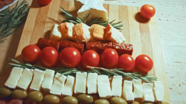 Plat leggen van kaas en tomaten. Stukjes kaas, tomaten en rozmarin in de vorm van een kerstboom. Eten voor kerstvakantie. Rotatie. Langzame beweging. - Video