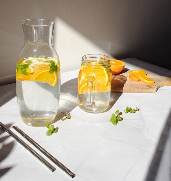 Νερό φρούτων. Νερό με λεμόνι και πορτοκάλι. Σε λευκό φόντο. - Φωτογραφία, εικόνα