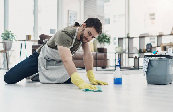 Getting rid of dirt and grime take some elbow grease. a young man wiping the floor at home - Photo, Image