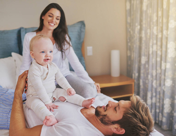 Happy mother, father and fun with baby in bedroom for love, care and quality time to relax together at home. Mom, dad and parents playing with infant kid for happiness, support or newborn development. - Foto, Imagem