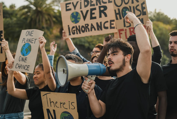 Grupa różnorodnych protestujących z tabliczkami z ilustracjami globu i megafonem krzyczącym z podniesionymi ramionami podczas demonstracji - Zdjęcie, obraz