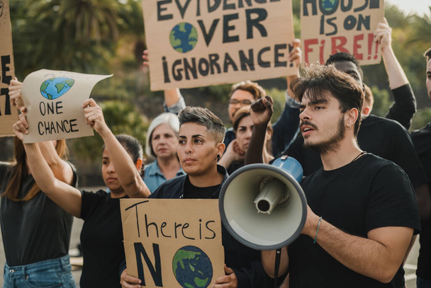 Groupe de manifestants multiethniques avec pancartes et homme avec haut-parleur représentant un problème écologique lors d'une manifestation dans la rue - Photo, image