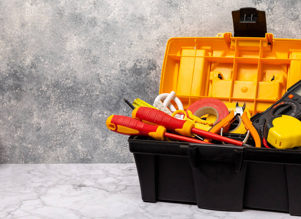 Electrician tools on white marble background.Multimeter,construction tape,electrical tape, screwdrivers,pliers,an automatic insulation stripper,socket and LED lamp.Flatley.electrician concept.Toolbox. - Foto, Imagem
