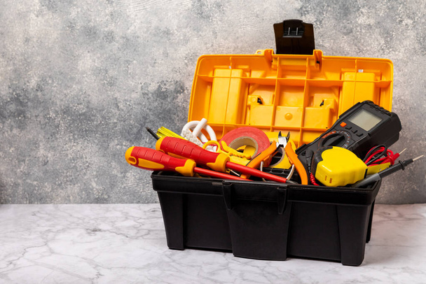 Electrician tools on white marble background.Multimeter,construction tape,electrical tape, screwdrivers,pliers,an automatic insulation stripper,socket and LED lamp.Flatley.electrician concept.Toolbox. - Fotoğraf, Görsel