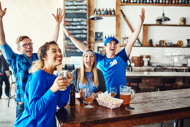 Tu ne peux pas battre le bleu. un groupe d'amis qui applaudissent en regardant un match de sport dans un bar - Photo, image
