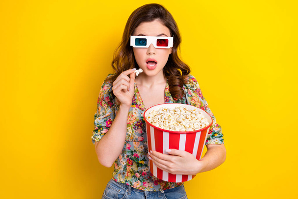 Portrait of impressed girl hand hold pop corn bucket open mouth watch movie 3d glasses isolated on yellow color background. - Foto, Bild