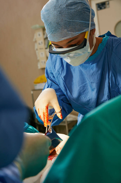 Steady hands and unwavering concentration are key. a team of surgeons performing a surgery in an operating room - Fotó, kép