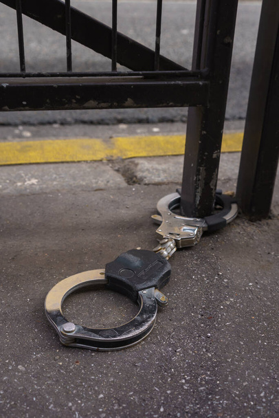 Handcuffs on pavement, attached to a metal railing on the street. Paris, France. - Foto, immagini