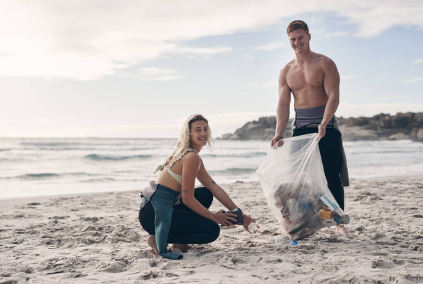 ¿Amas el océano lo suficiente como para cuidarlo? una pareja joven haciendo una limpieza de playa mientras usa trajes de neopreno - Foto, imagen