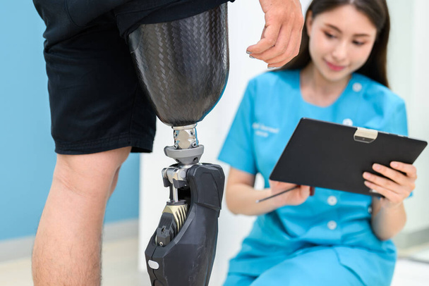 Fisioterapeuta femenina ajustando la pierna protésica de la paciente en el hospital, Paciente con discapacidad con tratamiento en el centro de atención médica, Nueva producción de extremidades artificiales para personas con discapacidad - Foto, Imagen