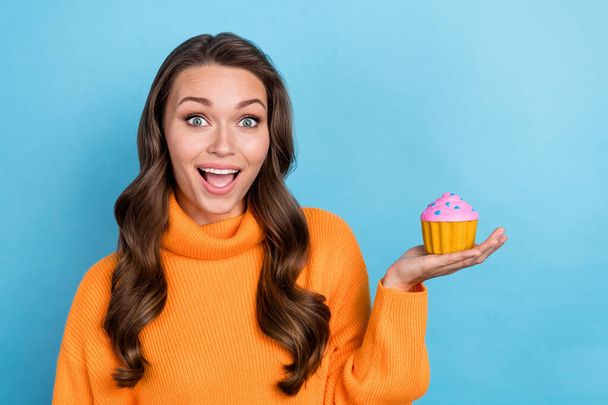Photo of surprised shocked lady holding tasty delicious glazed cream biscuit isolated on blue color background. - Foto, immagini