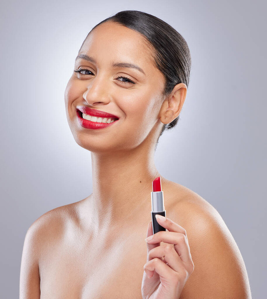 Todas las chicas deben tener un lápiz labial rojo. una atractiva joven mujer de pie sola en el estudio y posando mientras sostiene el lápiz labial rojo - Foto, imagen