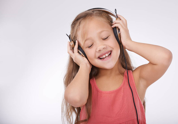 Nagyon zenés gyerek. Stúdiófelvétel egy kislányról, aki együtt énekel a zenével a fejhallgatóján. - Fotó, kép