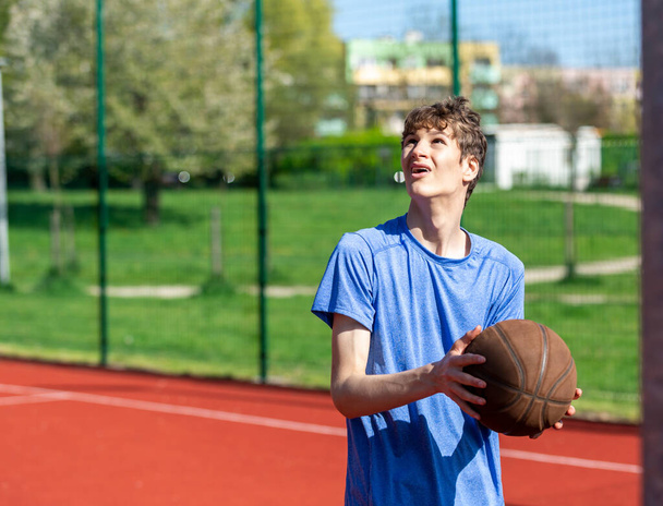 Хлопчик грає в баскетбол на дворі. Підліток біжить на стадіоні. Спорт, хобі, активний спосіб життя для хлопчиків
 - Фото, зображення