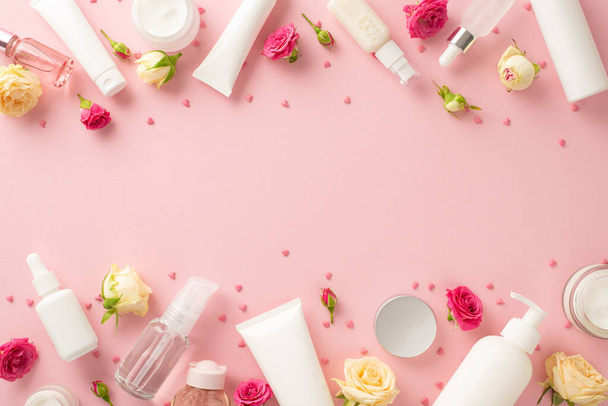 Natural skincare never looked so beautiful! This top view flat lay showcases cream bottles, pump bottles, pipettes, and roses on a pastel pink background with an empty space for branding or messaging - Photo, Image