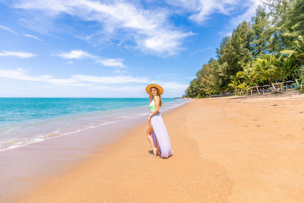 The summer lifestyle of a pretty young girl walking along the ocean coastline captures the essence of a carefree tropical vacation. Holidays at Asia, Thailand - 写真・画像
