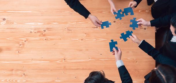 Top view businesspeople and colleagues in formal wear putting jigsaw puzzles together over meeting table with financial report papers in harmony office for team building concept. - Foto, immagini