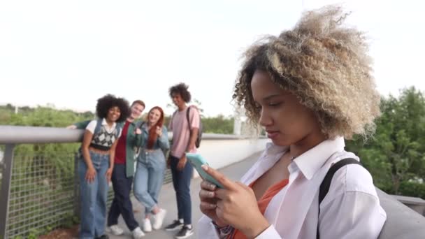 concepto de bullying estudiantes, grupo de jóvenes se ríen de una chica que está utilizando su teléfono inteligente - Imágenes, Vídeo